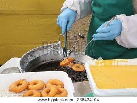 Cook With Gloves During The Preparation Of Fried Pancakes In The Boiling Oil
