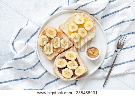 Banana Peanut Butter Toasts On White Plate. Vegan Snack Or Breakfast. Delicious Nut Butter, Bread An