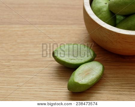 A Group Of Green Hog Plums Fruit, Which Look Like Small Mango, In Wooden Bowl Over Bright Wooden Bac