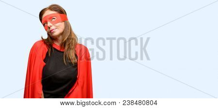 Middle age super hero woman wearing red mask and cape thinking and looking up expressing doubt and wonder isolated blue background