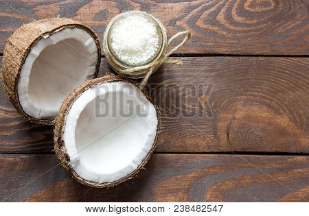 Two Halves Of Coconut And Coconut In A Glass Jar On A Wooden Table