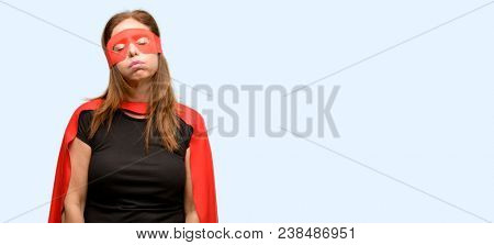 Middle age super hero woman wearing red mask and cape with sleepy expression, being overworked and tired isolated blue background