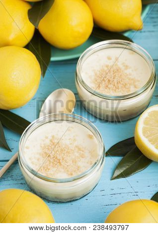 Glass Jar With Lemon Cheesecake With Fresh Lemons On Bluw Wooden Background