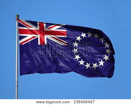 National Flag Of Cook Islands On A Flagpole In Front Of Blue Sky.