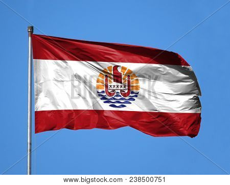 National Flag Of French Polynesia On A Flagpole In Front Of Blue Sky.