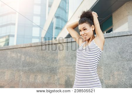 Young Female Runner Warming Up Before Running In The City, Against Modern Office Center, Copy Space