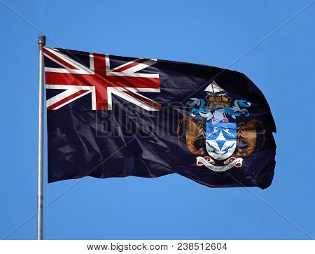 National Flag Of Tristan Da Cunha On A Flagpole In Front Of Blue Sky.