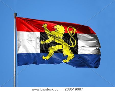 National Flag Of Benelux On A Flagpole In Front Of Blue Sky.
