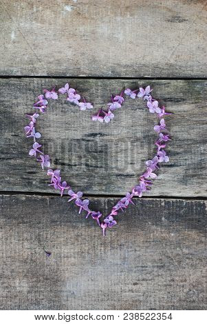 Spring Flowers. Lilac Flowers Frame Heart Shape Textured Rustic Gray Wooden Background.