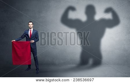 Businessman standing with red cloth on his hand and strong hero shadow on the background