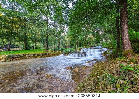 Little beautiful tourist town on the river Korana. Croatia, Slunj. Cascade waterfalls are lit by sunset rays. The concept of ecological and photo tourism