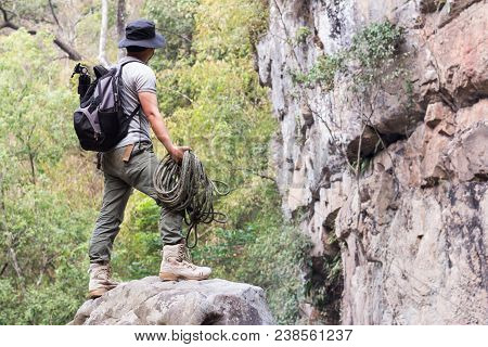 The Climber Holds The Rope In His Hands, Standing On A Rock.