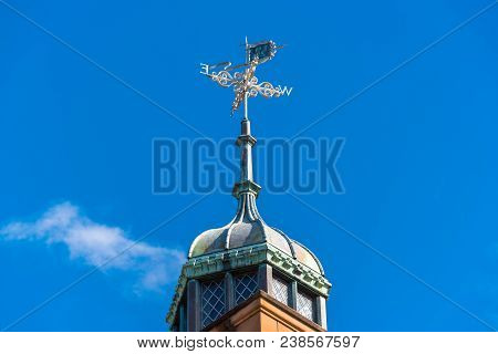 Vintage Weatherclock On Top Of Old Building Against Blue Sky On The Background