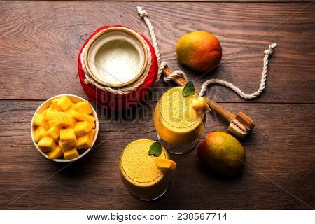 Mango Lassi Or Smoothie In Big Glass Or Small Bottles With Curd, Cut Fruit Pieces And Blender. Moody