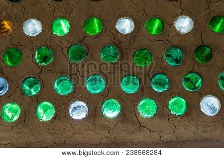 Colorful Sunlit Bottles In A Clay Cob Wall, Bottle Wall Mosaic. Ecological Building From Natural And