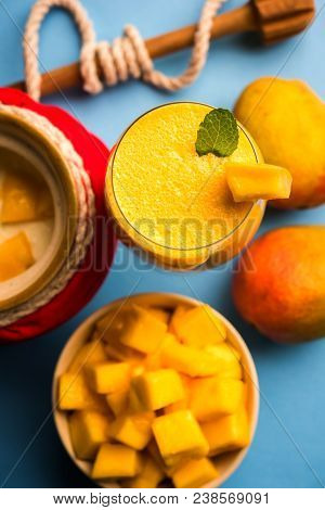 Mango Lassi Or Smoothie In Big Glass Or Small Bottles With Curd, Cut Fruit Pieces And Blender. Moody