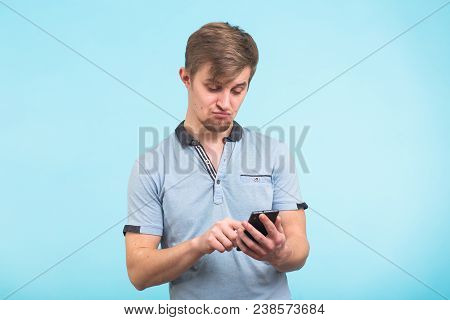 Funny Man Texting Message On Smart Phone Isolated On Grey Background. Smiling Guy Holding Smartphone