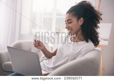 Pleasant Activity. Cheerful Happy Woman Sitting In Front Of The Laptop With A Credit Card While Doin