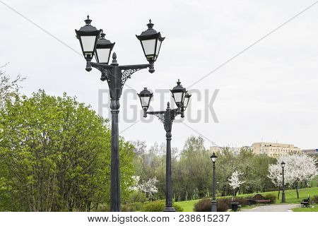 Black Metal Lantern With Two Tourist Sign In A Green Park. Black Lantern In A The Background Of Tree