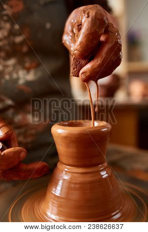 Close-up Hands Of A Male Potter In Plaid Shirt And Dirty Apron Who Molds A Vase From Clay, Selective