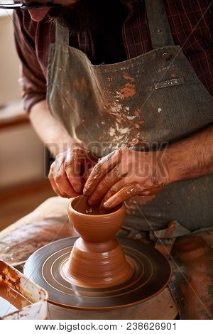 Close-up Hands Of A Male Potter In Plaid Shirt And Dirty Apron Who Molds A Vase From Clay, Selective