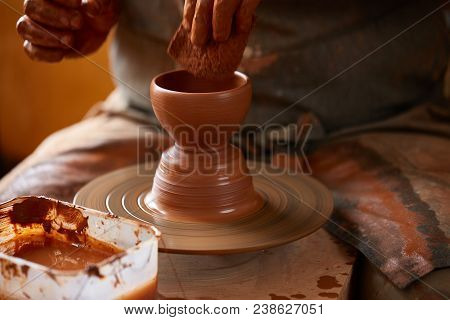 Close-up Hands Of A Male Potter In Plaid Shirt And Dirty Apron Who Molds Bowl From Clay, Selective F