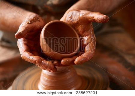 Close-up Hands Of A Male Potter In Plaid Shirt And Dirty Apron Who Molds Bowl From Clay, Selective F