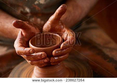 Close-up Hands Of A Male Potter In Plaid Shirt And Dirty Apron Who Molds Bowl From Clay, Selective F