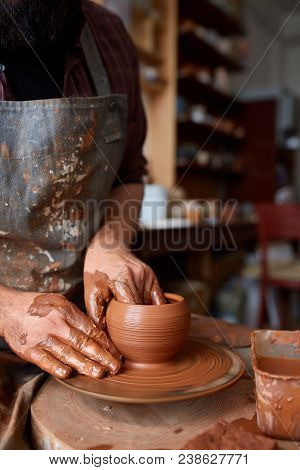Portrait Of A Handsome Bearded Male Potter In Plaid Shirt And Dirty Apron Who Molds Bowl From Clay, 