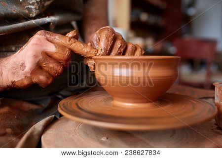 Close-up Hands Of A Male Potter In Plaid Shirt And Dirty Apron Who Molds Bowl From Clay, Selective F
