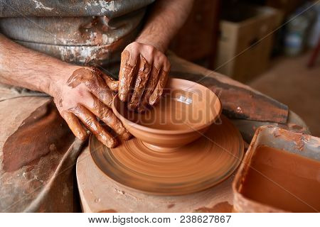Close-up Hands Of A Male Potter In Plaid Shirt And Dirty Apron Who Molds Bowl From Clay, Selective F