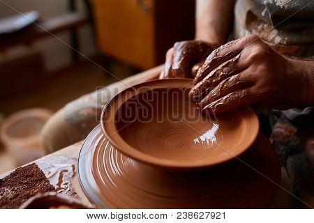 Close-up Hands Of A Male Potter In Plaid Shirt And Dirty Apron Who Molds Bowl From Clay, Selective F
