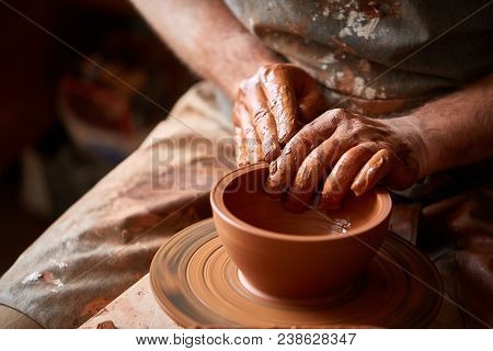 Close-up Hands Of A Male Potter In Plaid Shirt And Dirty Apron Who Molds Bowl From Clay, Selective F