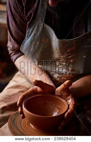 Close-up Hands Of A Male Potter In Plaid Shirt And Dirty Apron Who Molds Bowl From Clay, Selective F