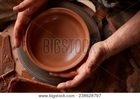 Close-up Hands Of A Male Potter In Plaid Shirt And Dirty Apron Who Molds Bowl From Clay, Selective F