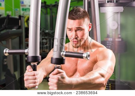 Mixed Race Fitness Man Is Working Out On Butterfly Machine In Gym.