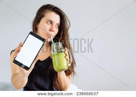 Young Pretty Woman Portrait Drink Smoothie And Show Shite Screen In Smartphone. White Background. Co