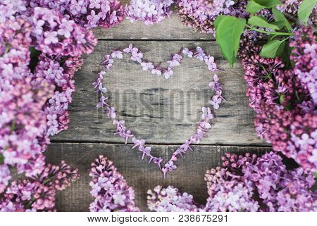 Spring Flowers. Lilac Flowers Frame Heart Shape Textured Rustic Gray Wooden Background.