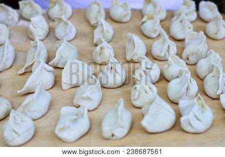 Multiple Chinese Uncooked Dumplings Placed On Wooden Board.  The Dumplings, Called Jiaozi In Chinese