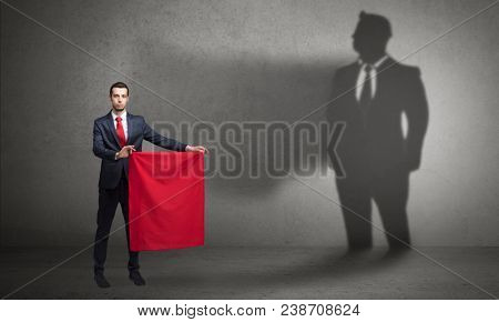Businessman standing with red cloth on his hand and his shadow on the background