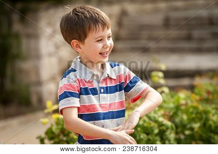 Happy Cute Caucasian Kid Playing With Water Fountain In The Public Park.