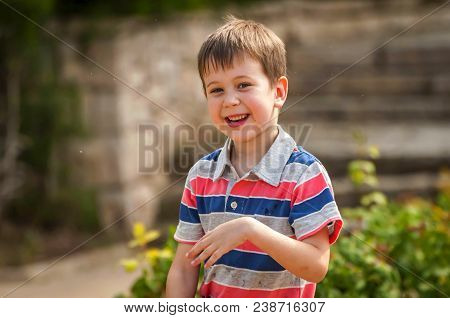 Happy Cute Caucasian Kid Playing With Water Fountain In The Public Park.