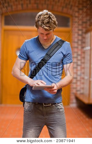 Portret przystojny student za pomocą komputera typu tablet w korytarzu