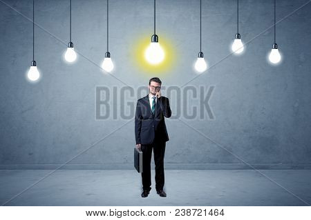 Handsome businessman in an empty space with bulbs above and uninspired face
