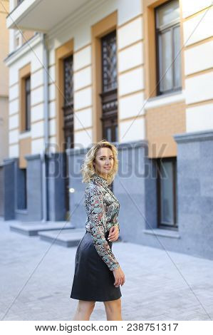 Pretty Female Photo Model Standing Near Building And Wearing Leather Skirt. Oncept Of Vogue And Fash