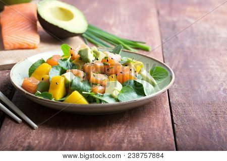 Hawaiian Poke Salad With Salmon, Avocado And Vegetables On A Plate On A Rustic Background. Close Up