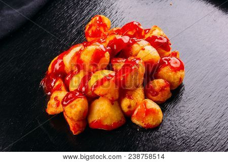 Typical Spanish Food, Patatas Bravas, Fried Potatoes With A Hot Sauce, On A Dark Background
