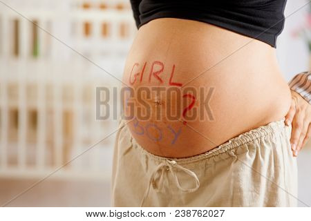 Close-up of pregnant belly with drawn question mark and text asking boy or girl.