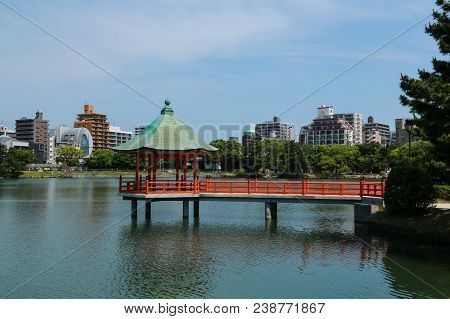 Red Pagoda With Green Roof Surround By Water In Ohori Park, Fukuoka, Japan
