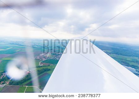 Wing of a flying sport plane with landscape underneath